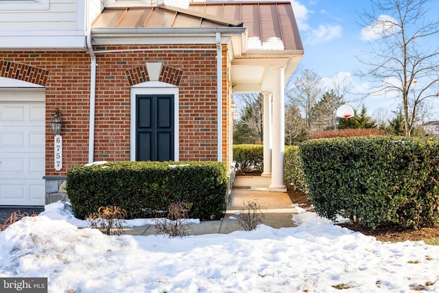 snow covered property entrance with a garage