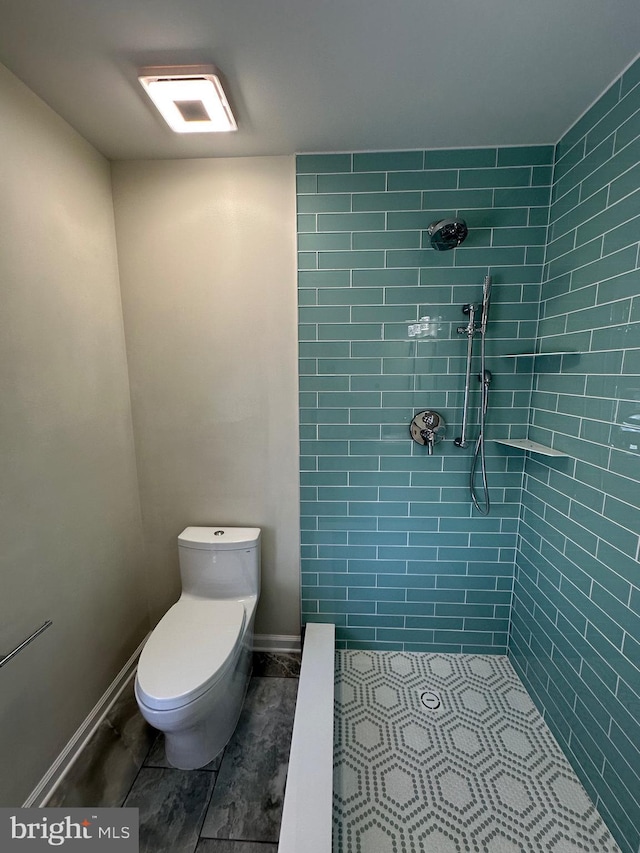 bathroom with tiled shower and toilet