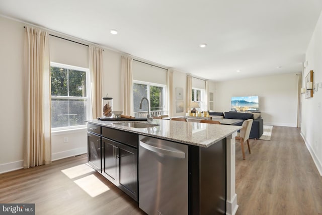 kitchen with a wealth of natural light, stainless steel dishwasher, a kitchen island with sink, and sink