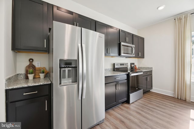 kitchen with light stone counters, light hardwood / wood-style flooring, and appliances with stainless steel finishes