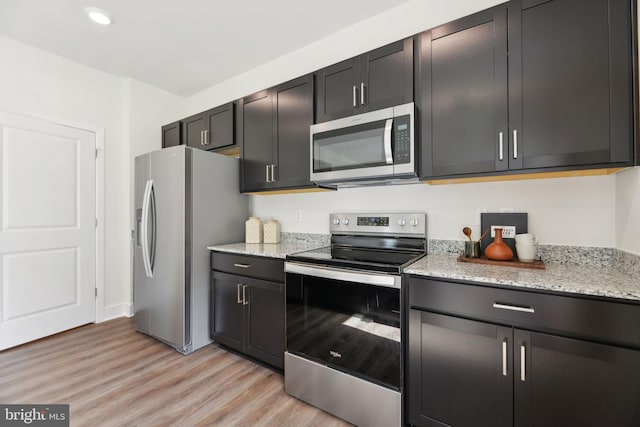 kitchen featuring light stone countertops, appliances with stainless steel finishes, and light hardwood / wood-style flooring