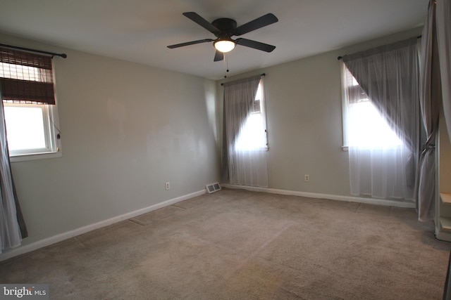 empty room with ceiling fan and light carpet