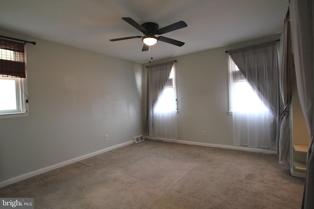 unfurnished room featuring plenty of natural light, ceiling fan, and light colored carpet