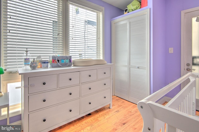 bedroom featuring light wood-type flooring, a nursery area, and a closet