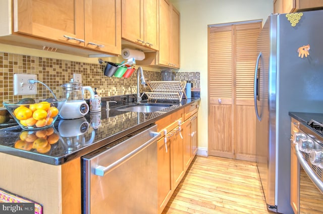 kitchen with tasteful backsplash, dark stone countertops, sink, and appliances with stainless steel finishes