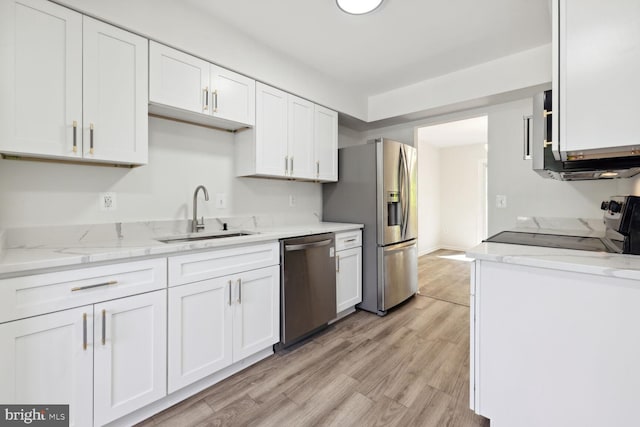 kitchen with sink, stainless steel appliances, light stone counters, light hardwood / wood-style flooring, and white cabinets