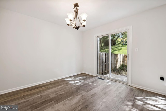 empty room with dark hardwood / wood-style flooring and a chandelier