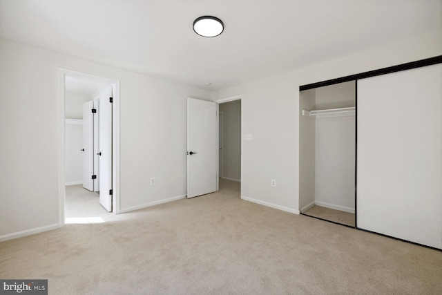 unfurnished bedroom with light colored carpet and a closet