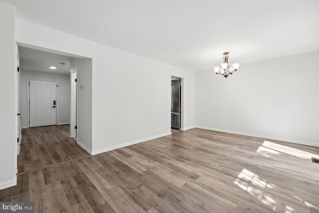 unfurnished room with hardwood / wood-style flooring and a notable chandelier