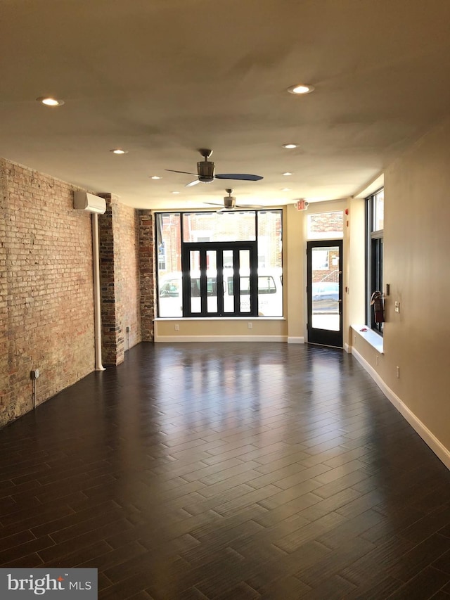 unfurnished room featuring ceiling fan, dark hardwood / wood-style floors, and brick wall