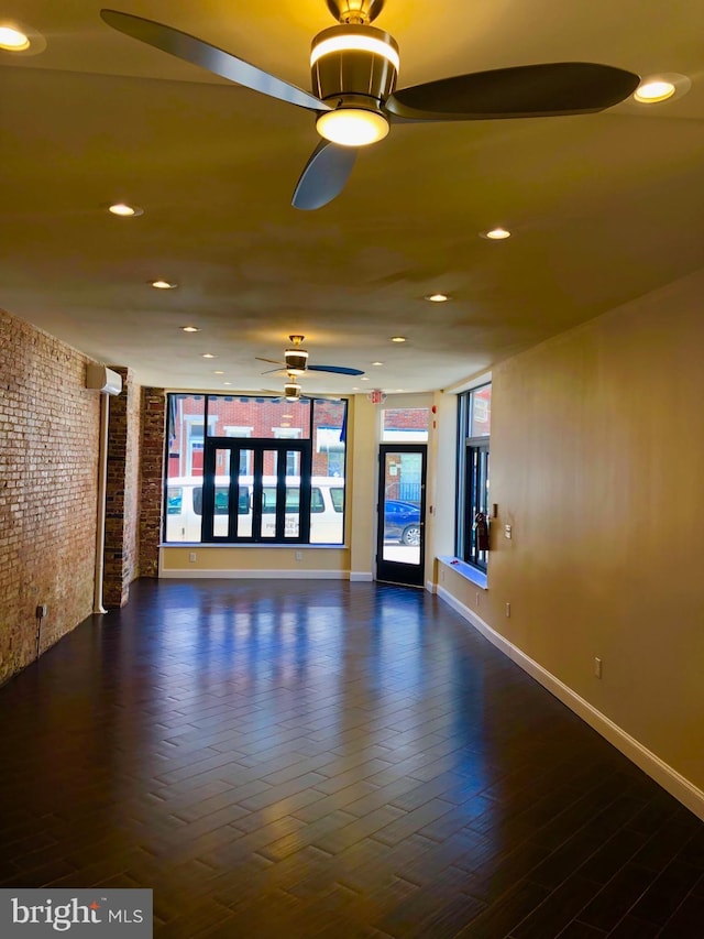 unfurnished room with ceiling fan, dark wood-type flooring, and brick wall