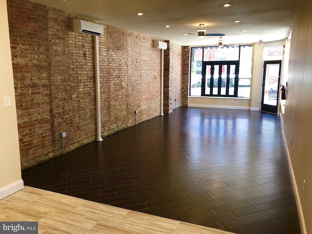 spare room with ceiling fan, brick wall, and a wall mounted AC