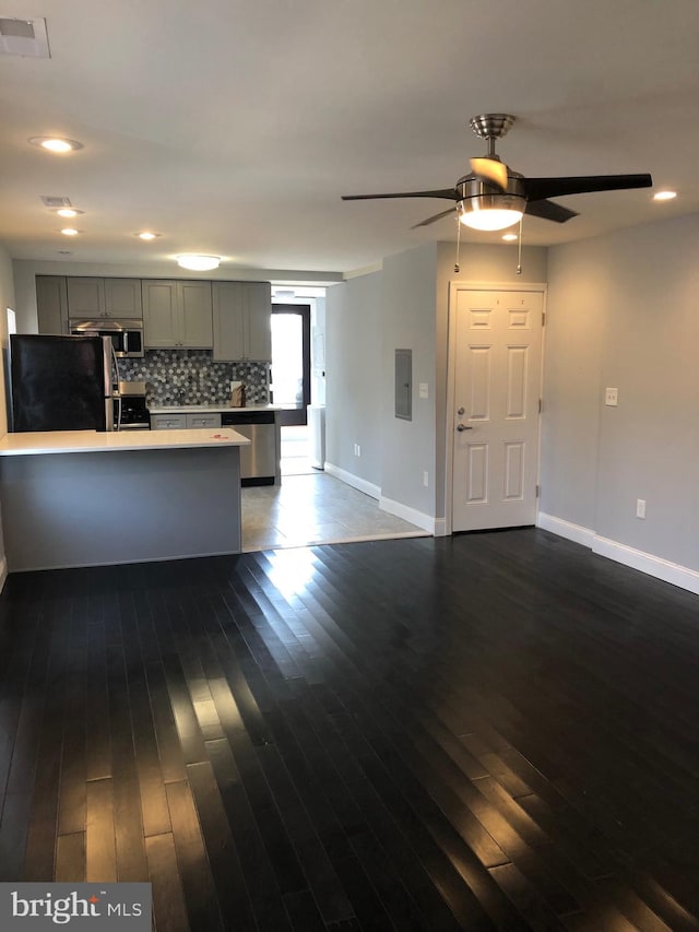 kitchen featuring gray cabinets, appliances with stainless steel finishes, backsplash, dark hardwood / wood-style flooring, and electric panel