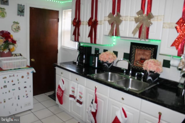 kitchen featuring decorative backsplash, light tile patterned floors, white cabinetry, and sink