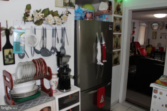 kitchen featuring white cabinets, stainless steel fridge, and light tile patterned floors