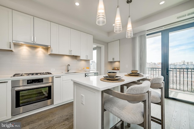 kitchen featuring white cabinetry, pendant lighting, sink, and stainless steel oven