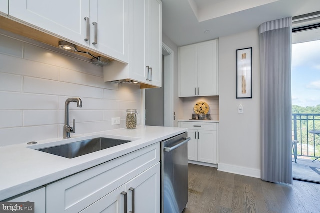 kitchen with dark wood-type flooring, sink, stainless steel dishwasher, white cabinets, and backsplash