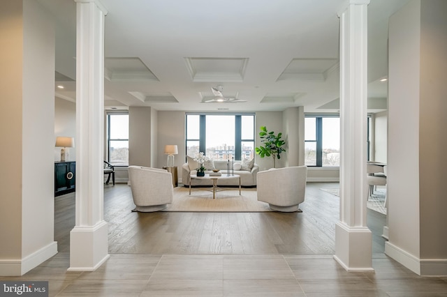 living room with decorative columns, a wealth of natural light, and light hardwood / wood-style floors