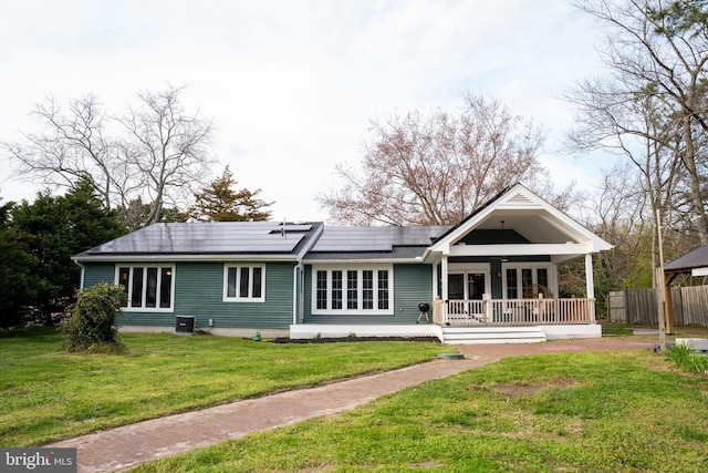 back of property with a lawn, central air condition unit, solar panels, and a porch