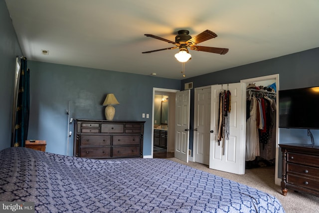 bedroom with ceiling fan, ensuite bath, light carpet, and multiple closets