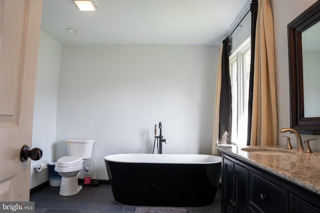 bathroom featuring a washtub, toilet, vanity, and tile patterned flooring