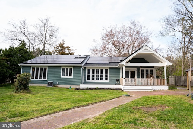 rear view of house featuring a yard, a porch, cooling unit, and solar panels