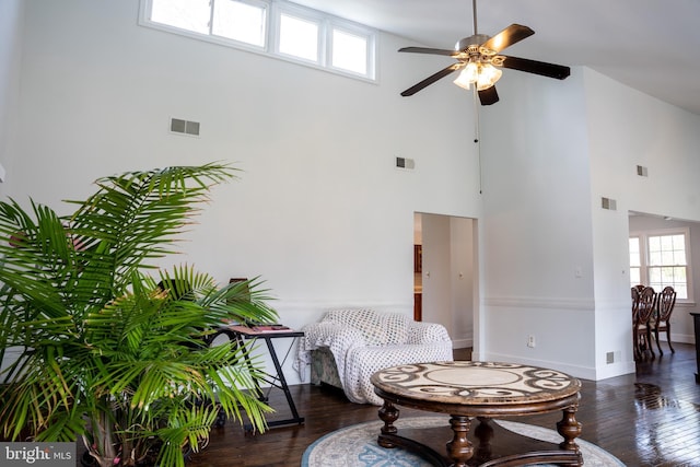 sitting room featuring ceiling fan, dark hardwood / wood-style floors, and a towering ceiling