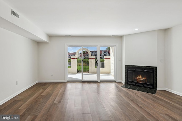 unfurnished living room featuring dark hardwood / wood-style flooring and a tile fireplace