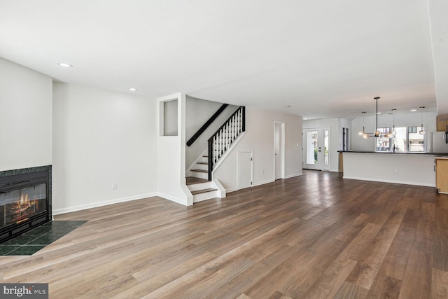 unfurnished living room featuring a tile fireplace and hardwood / wood-style flooring