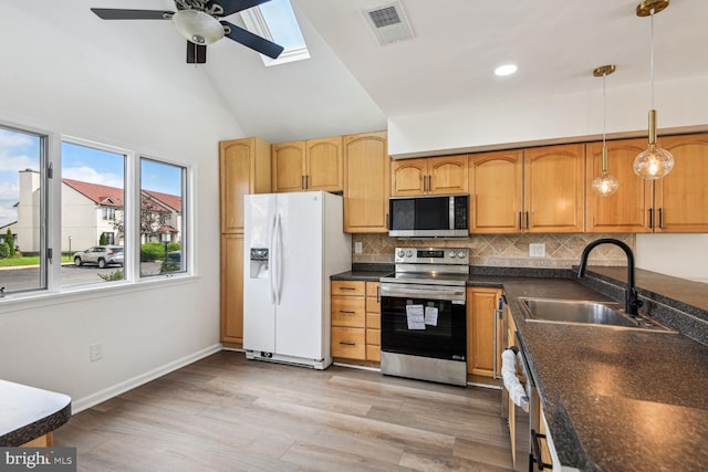 kitchen featuring decorative backsplash, appliances with stainless steel finishes, vaulted ceiling, sink, and pendant lighting