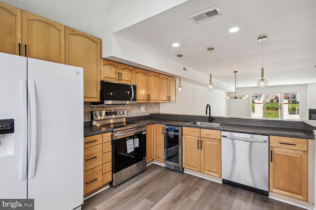 kitchen featuring decorative backsplash, appliances with stainless steel finishes, sink, wine cooler, and hanging light fixtures