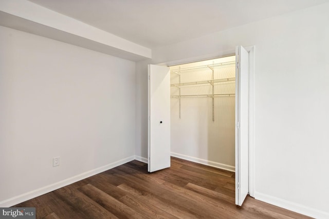 unfurnished bedroom featuring a closet and dark wood-type flooring