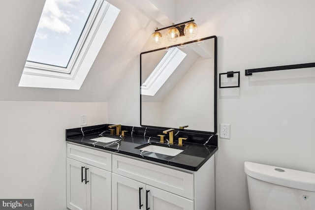 bathroom featuring vaulted ceiling with skylight, vanity, and toilet