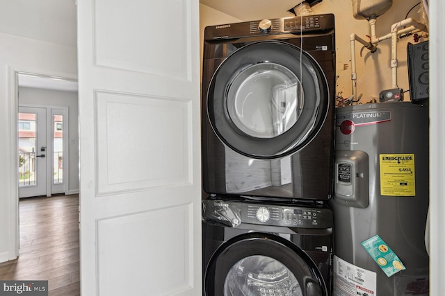 washroom featuring electric water heater, stacked washer and dryer, and hardwood / wood-style floors