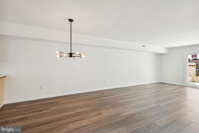 empty room with hardwood / wood-style floors and an inviting chandelier