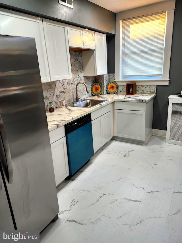 kitchen featuring white cabinetry, sink, stainless steel appliances, light stone counters, and decorative backsplash