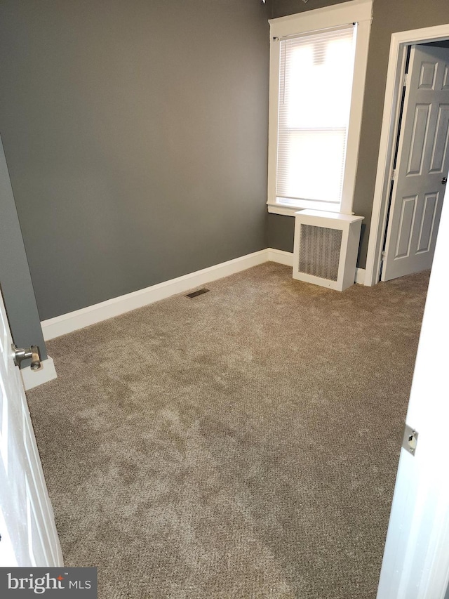 carpeted spare room featuring radiator