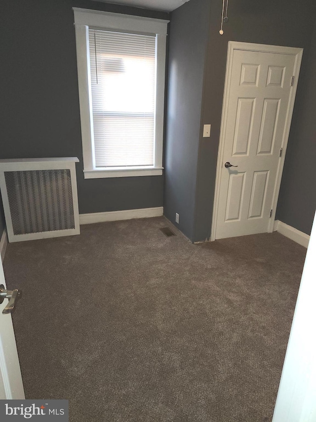 unfurnished room featuring dark carpet