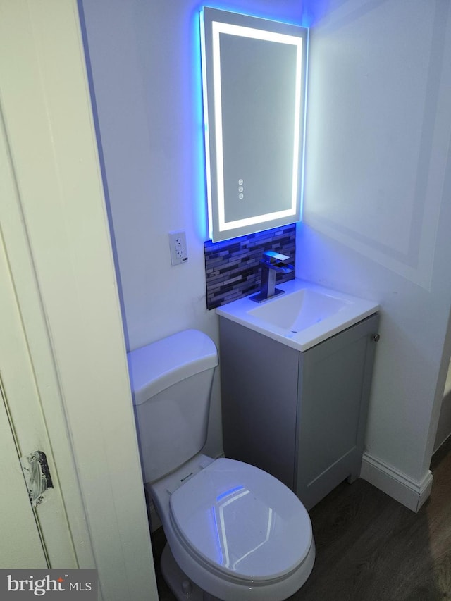 bathroom featuring decorative backsplash, toilet, wood-type flooring, and vanity