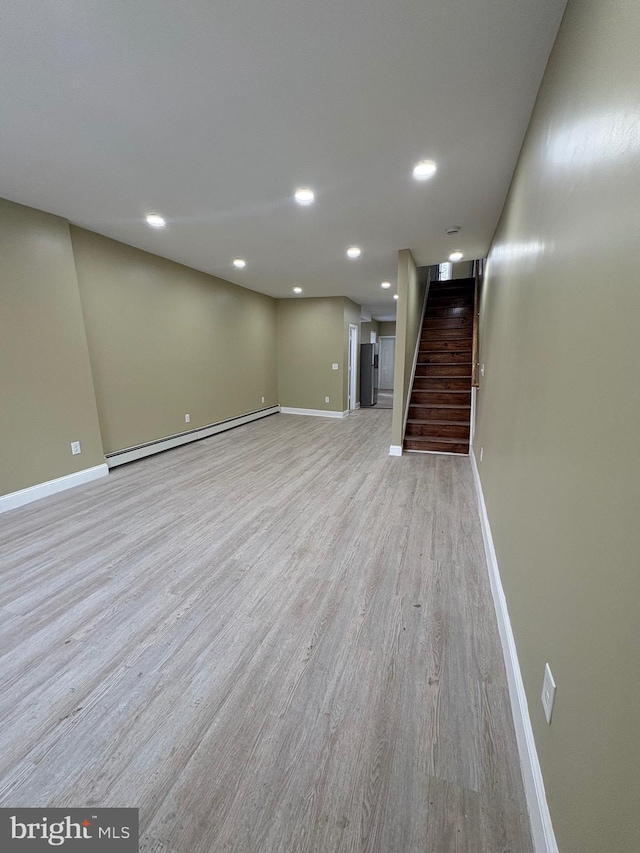 basement featuring a baseboard radiator and light hardwood / wood-style flooring