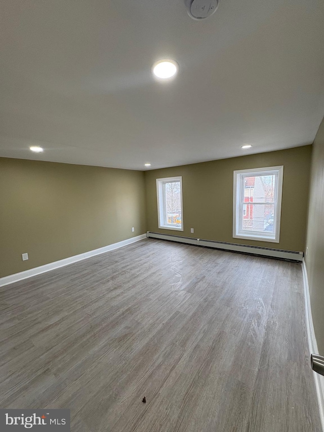 empty room with a baseboard radiator and light hardwood / wood-style floors