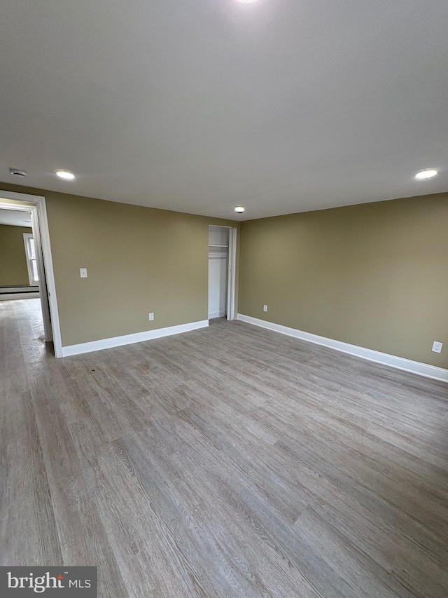 unfurnished room with light hardwood / wood-style flooring and a baseboard heating unit