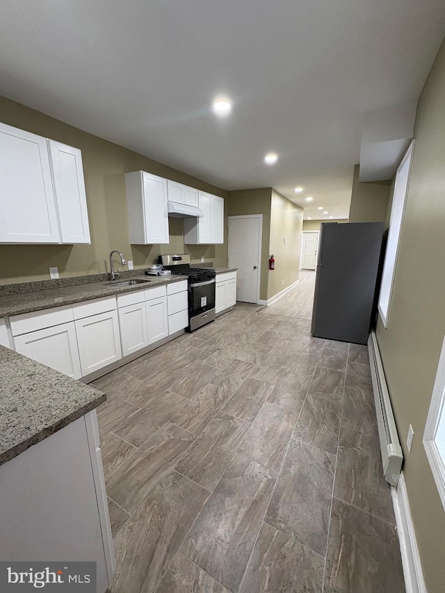 kitchen with stainless steel appliances, sink, white cabinets, dark stone counters, and a baseboard radiator