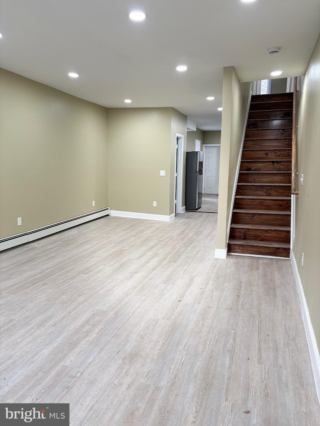 unfurnished living room with light wood-type flooring and a baseboard heating unit