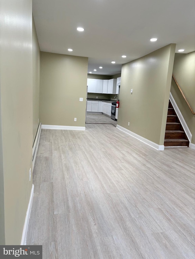 basement with light wood-type flooring and a baseboard radiator