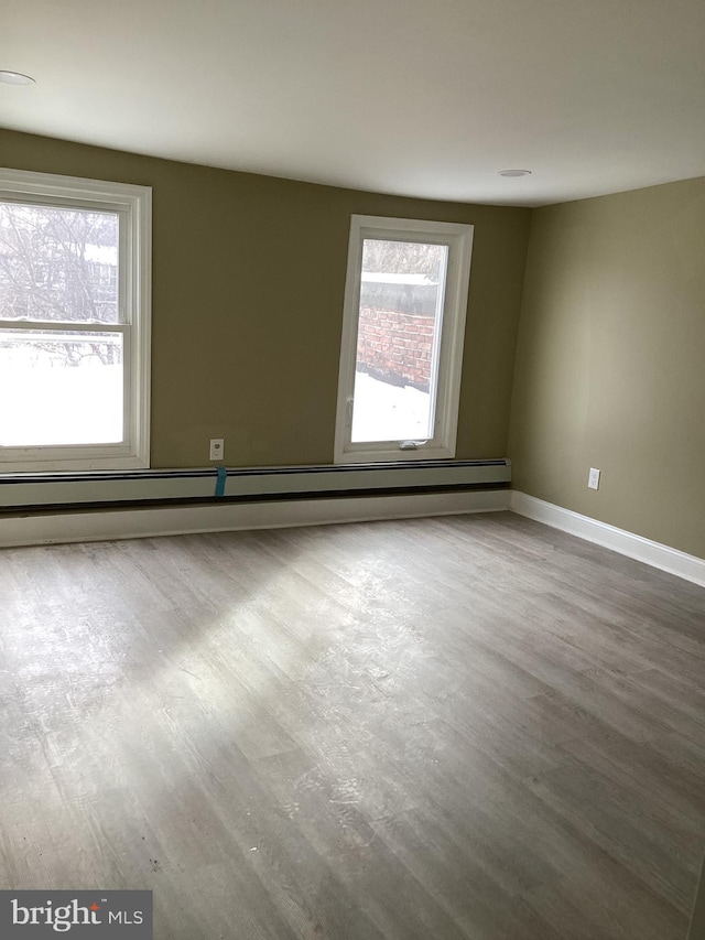 spare room with a baseboard radiator, hardwood / wood-style floors, and plenty of natural light