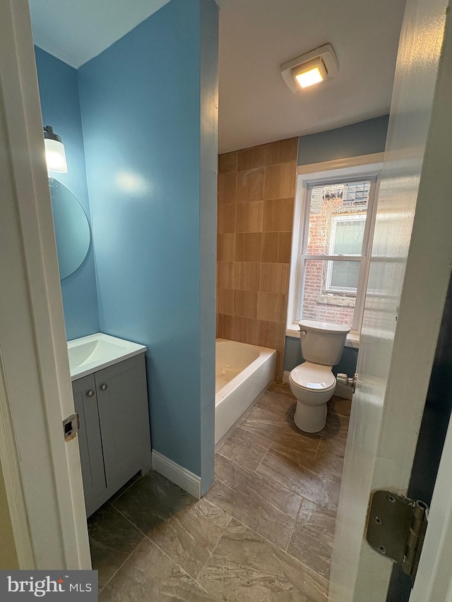 bathroom with toilet, a bath, and vanity