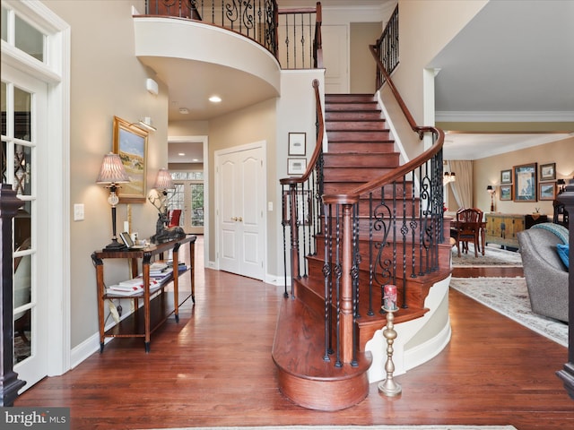 entryway with ornamental molding and dark wood-type flooring