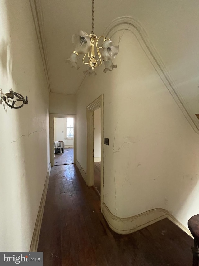 hallway with vaulted ceiling, an inviting chandelier, and dark wood-type flooring