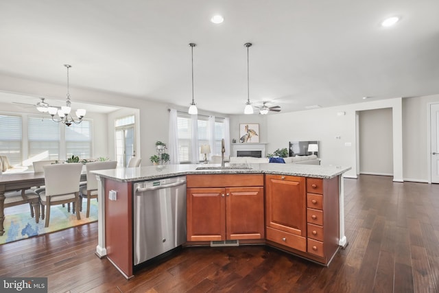 kitchen with dishwasher, sink, light stone counters, and an island with sink